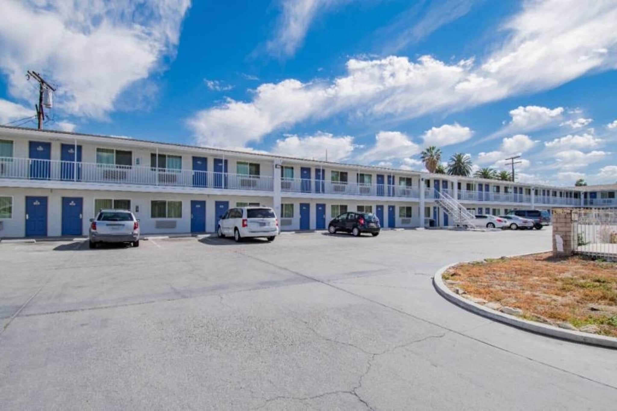 A motel with multiple rooms, a parking lot, and a clear sky.