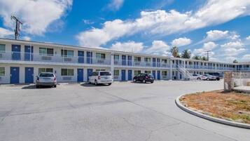 A motel with multiple rooms, a parking lot, and a clear sky.