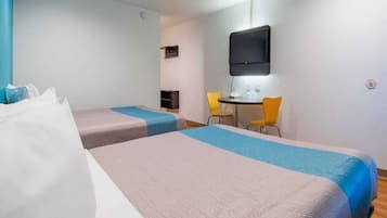 A hotel room with two beds, a desk, a chair, and a television.