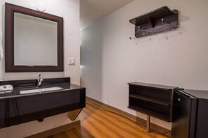 A bathroom with a dark countertop, a mirror, a sink, and a black cabinet. - Cozy King Bed|Smoking|Mini Fridge (San Bernardino)
