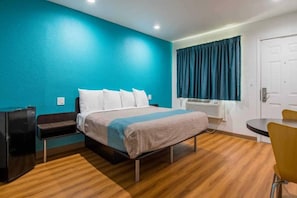 Een hotelkamer met een bed, een bureau, een stoel en een raam met gordijnen.