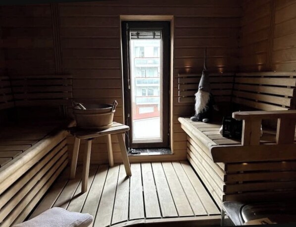 Una sauna amb seients de fusta, una taula petita amb un bol i una tovallola a terra.