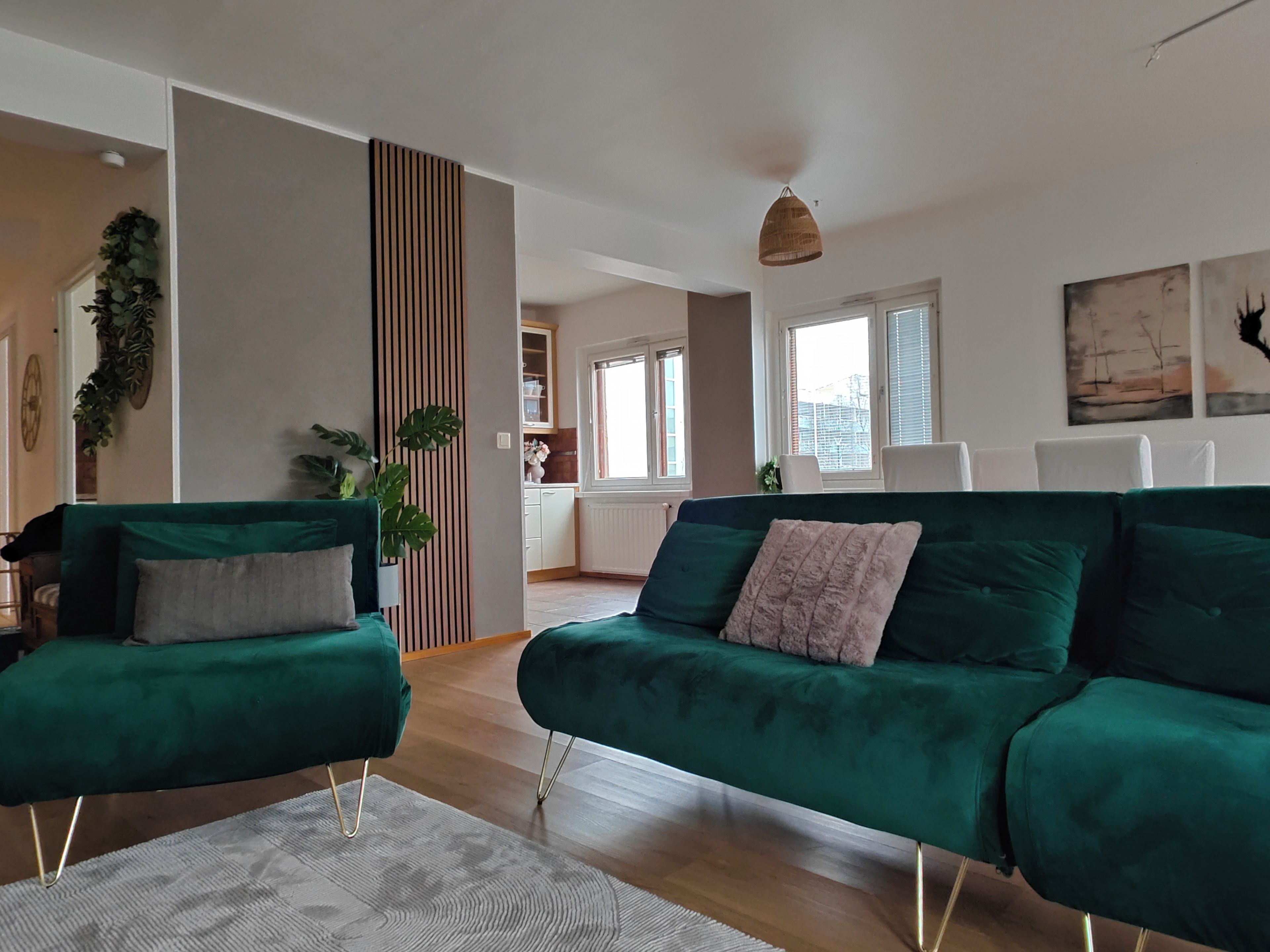 Un salon moderne avec un canapé vert, une table basse et une plante décorative.