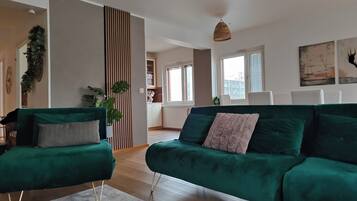 Un salon moderne avec un canapé vert, une table basse et une plante décorative.
