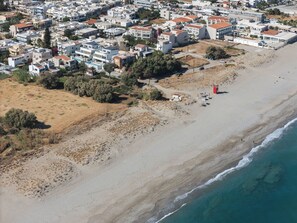 Eine Vogelperspektive auf eine Küstenwohngegend mit Gebäuden, einem Strand und einem Leuchtturm.