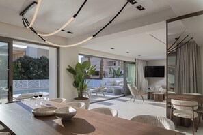 Een moderne woonkamer met een grote houten eettafel, comfortabele zitplaatsen, een flatscreen-tv en een balkon met tuinmeubilair.