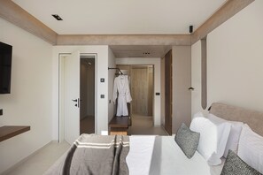 Ein modernes Schlafzimmer mit einem großen Bett, einem an der Wand befestigten Fernseher und einem begehbaren Kleiderschrank.
