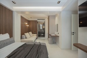 Ein modernes Schlafzimmer mit einem Bett, einem Sofa, einem kleinen Tisch und einem Spiegel.