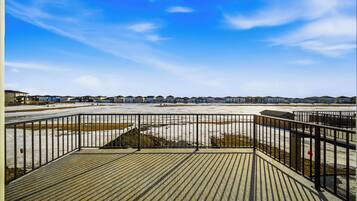A view from a wooden deck overlooking a residential area with houses and a clear sky.