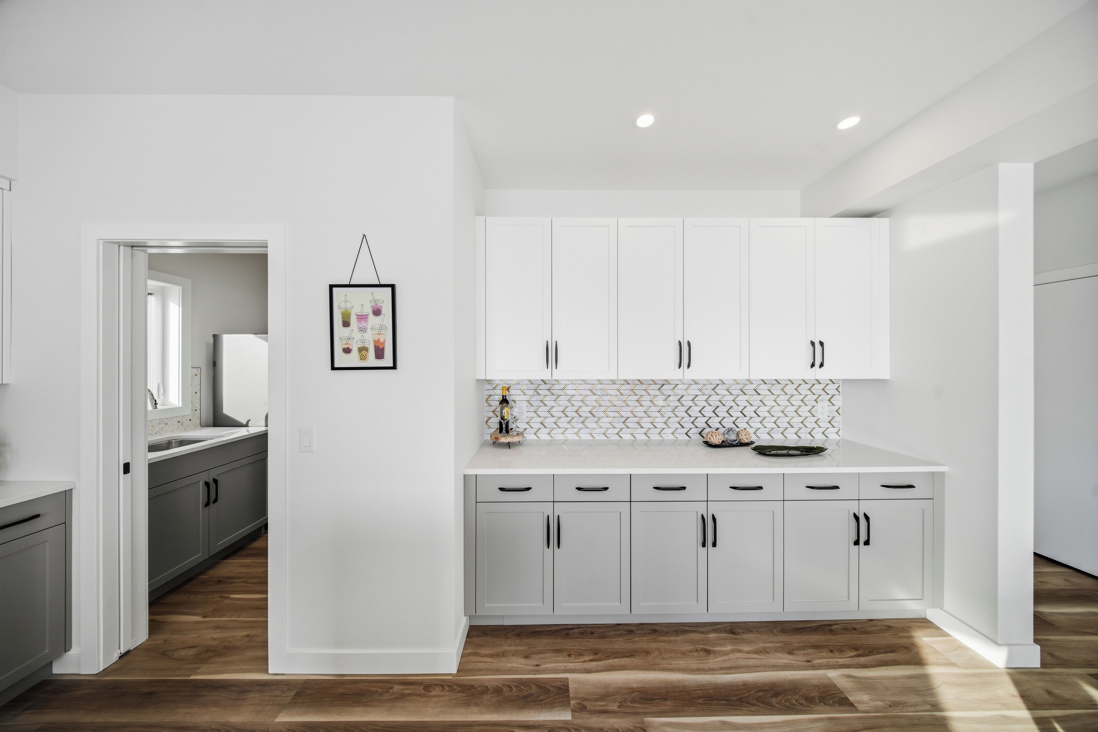 Cozinha moderna com armários brancos, painel de backsplash em mosaico de herringbone e piso de madeira.