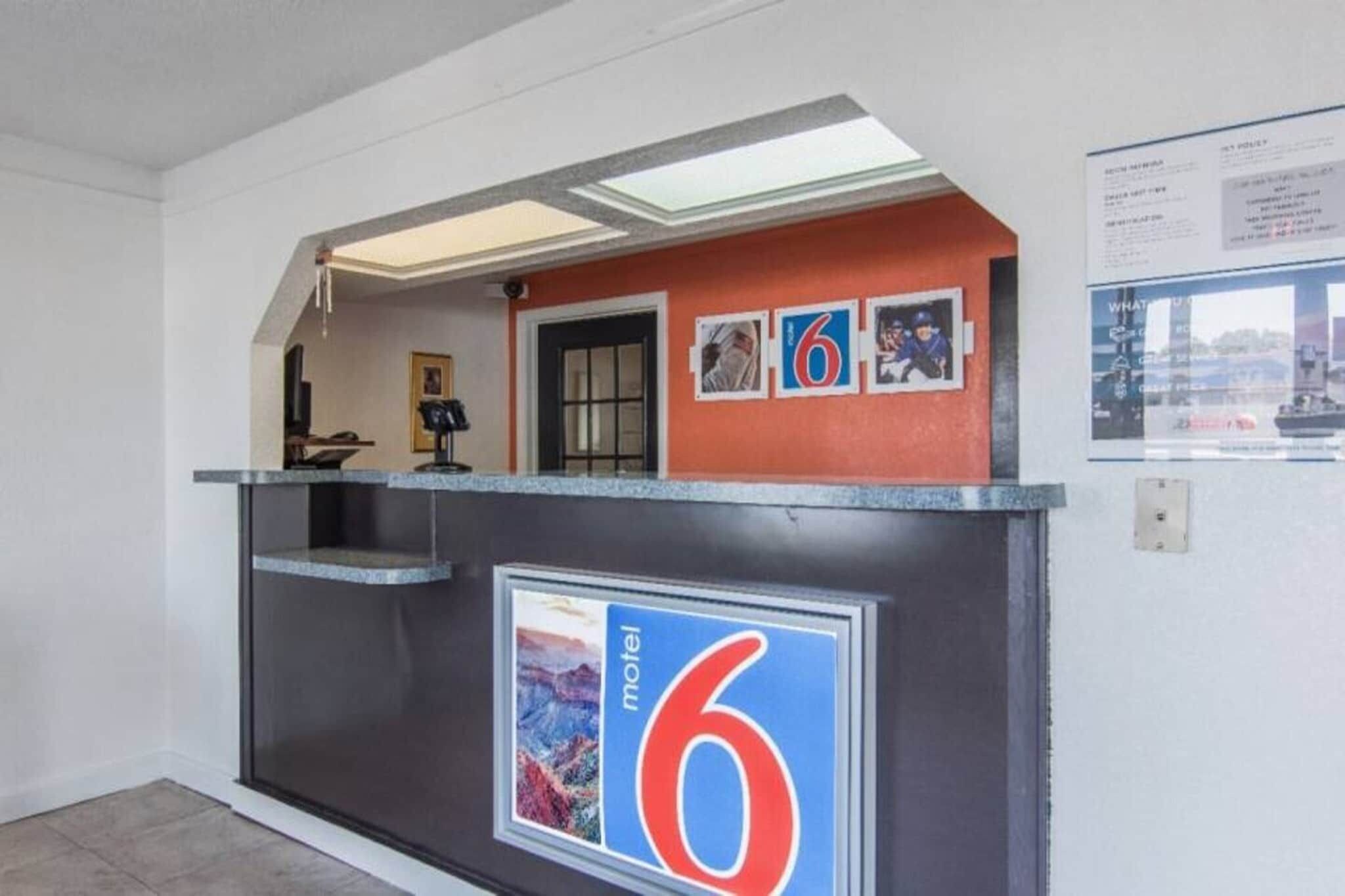 A reception desk with a number '6' sign, a framed picture, and a small shelf with items.