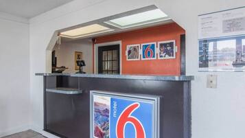 A reception desk with a number '6' sign, a framed picture, and a small shelf with items.