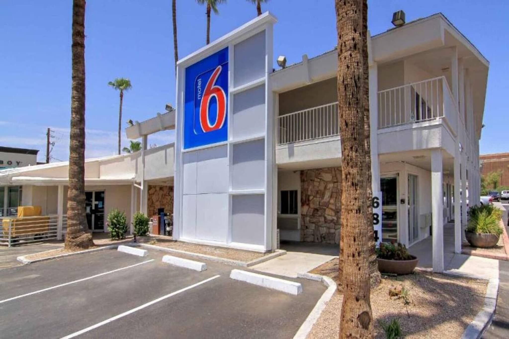Un motel reconnaissable à son grand panneau en forme de « 6 », une construction à deux étages et un parking.