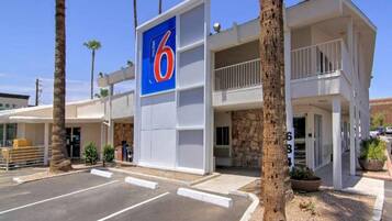 Un motel con un llamativo letrero con el número '6', una estructura de dos pisos y un estacionamiento.