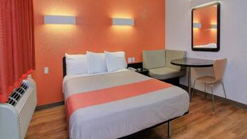 Una habitación de hotel con cama, escritorio, silla y espejo.