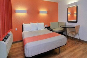 Una habitación de hotel con cama, escritorio, silla y espejo.