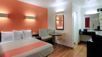 Habitación de hotel con cama, escritorio, silla, mesa redonda y espejo.