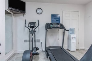 A fitness center with an elliptical machine, a treadmill, a water dispenser, and a clock on the wall. - 2 Queen Beds|Smoking| Micfridge (HOPE)