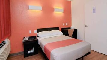A hotel room with a bed, bedside tables, a heater, and a door.