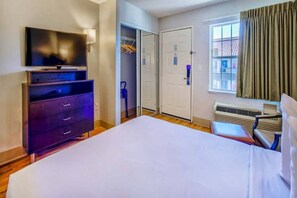 A hotel room with a bed, a flat-screen TV, a dresser, a closet, and a window with curtains. - Studio 6 Phoenix, Az - Deer Valley_1 Kin (PHOENIX)
