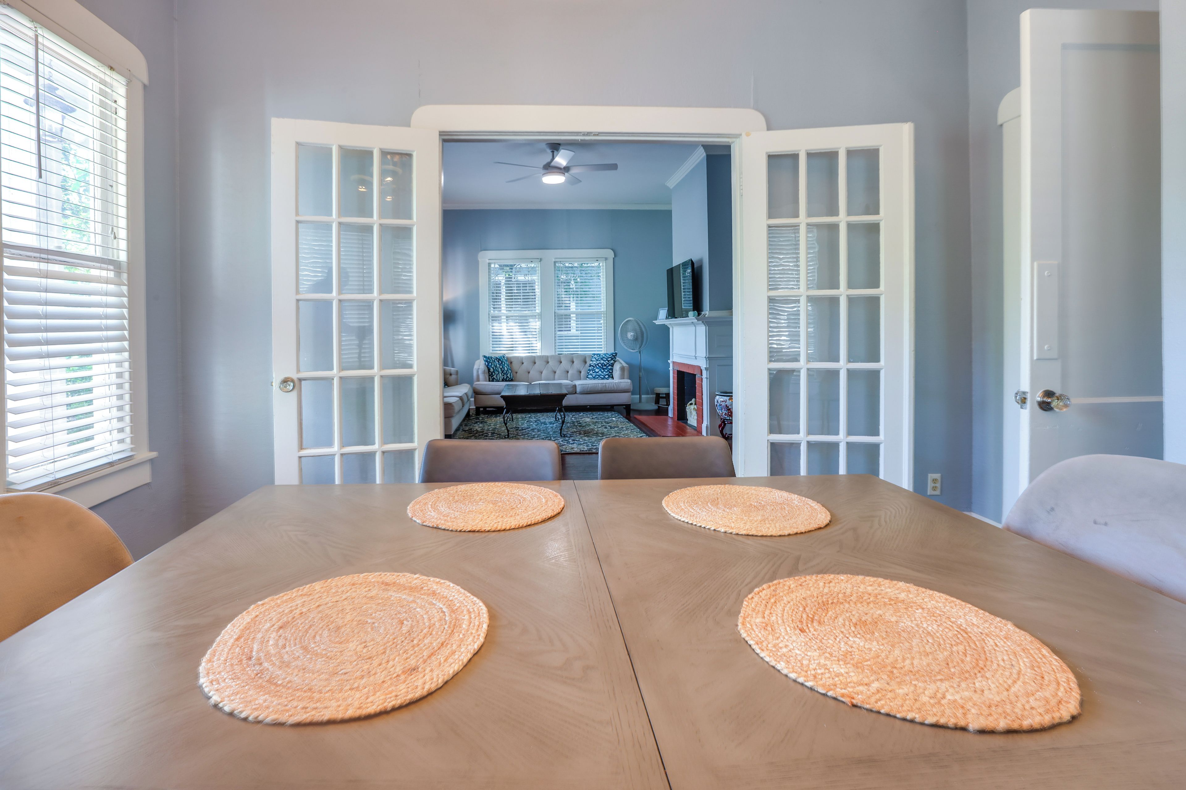Un coin repas avec une table en bois et quatre sets de table en fibres tressées.