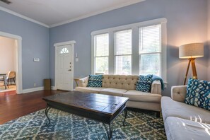A living room with a sofa, a coffee table, and a lamp. - Quaint North Campus Bungalow Minutes From Downtown (Austin)