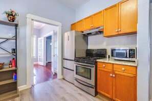 Une cuisine avec des meubles en bois, un réfrigérateur en acier inoxydable, une cuisinière et un four à micro-ondes.
