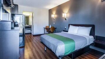 Una habitación de hotel con cama, escritorio, silla y kitchenette.