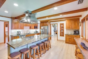 Una cocina amplia con una isla grande, armarios de madera y una campana extractora de acero inoxidable.
