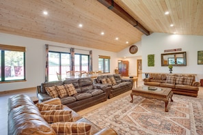 A spacious living room with a large leather sofa, a smaller sofa, and a coffee table. There are multiple windows providing natural light and a view of the outside. - Private Pool & Hot Tub! Luxe South Lake Tahoe Gem (South Lake Tahoe)