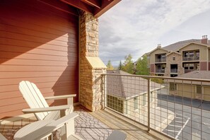 A wooden deck with a white Adirondack chair, a stone chimney, and a view of neighboring buildings. - Ski Granby Ranch! Condo w/ Community Hot Tub (Granby)
