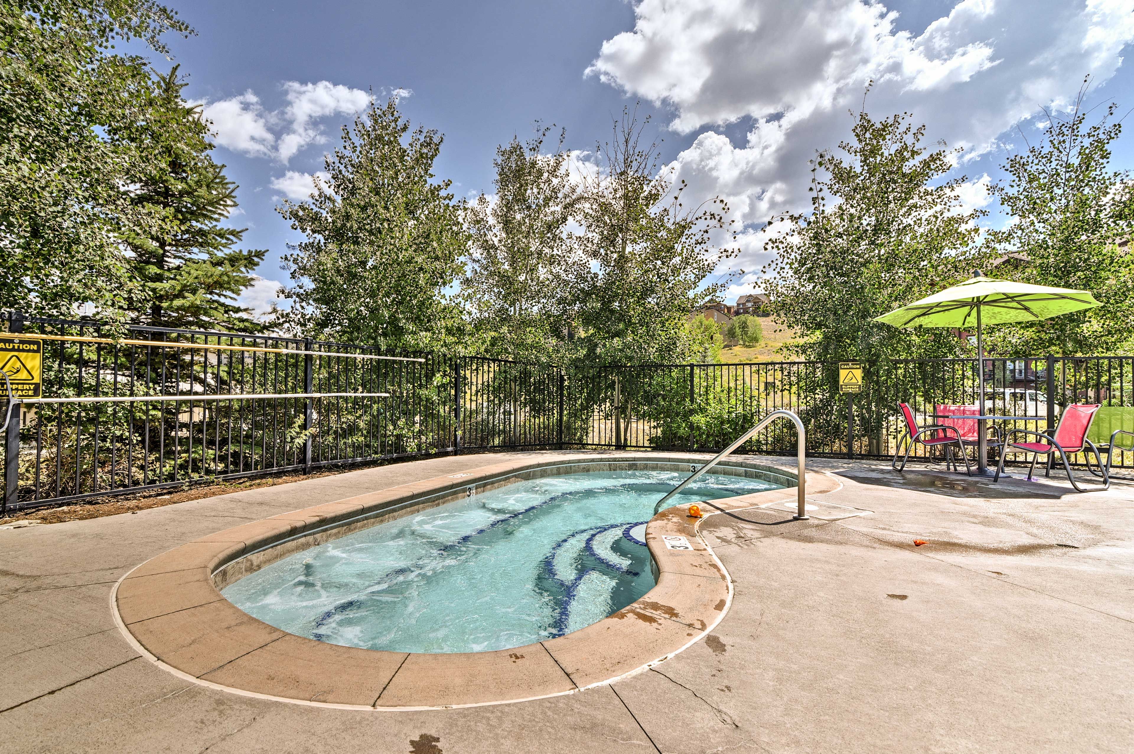 A swimming pool with a safety fence, a lifeguard chair, and a caution sign.