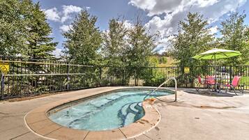 A swimming pool with a safety fence, a lifeguard chair, and a caution sign.