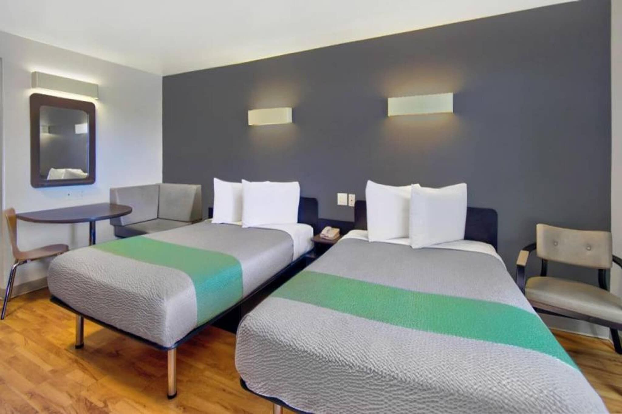 Ett hotellrum med två sängar, ett litet bord, en stol och en spegel.