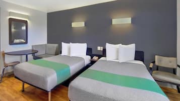 Ett hotellrum med två sängar, ett litet bord, en stol och en spegel.