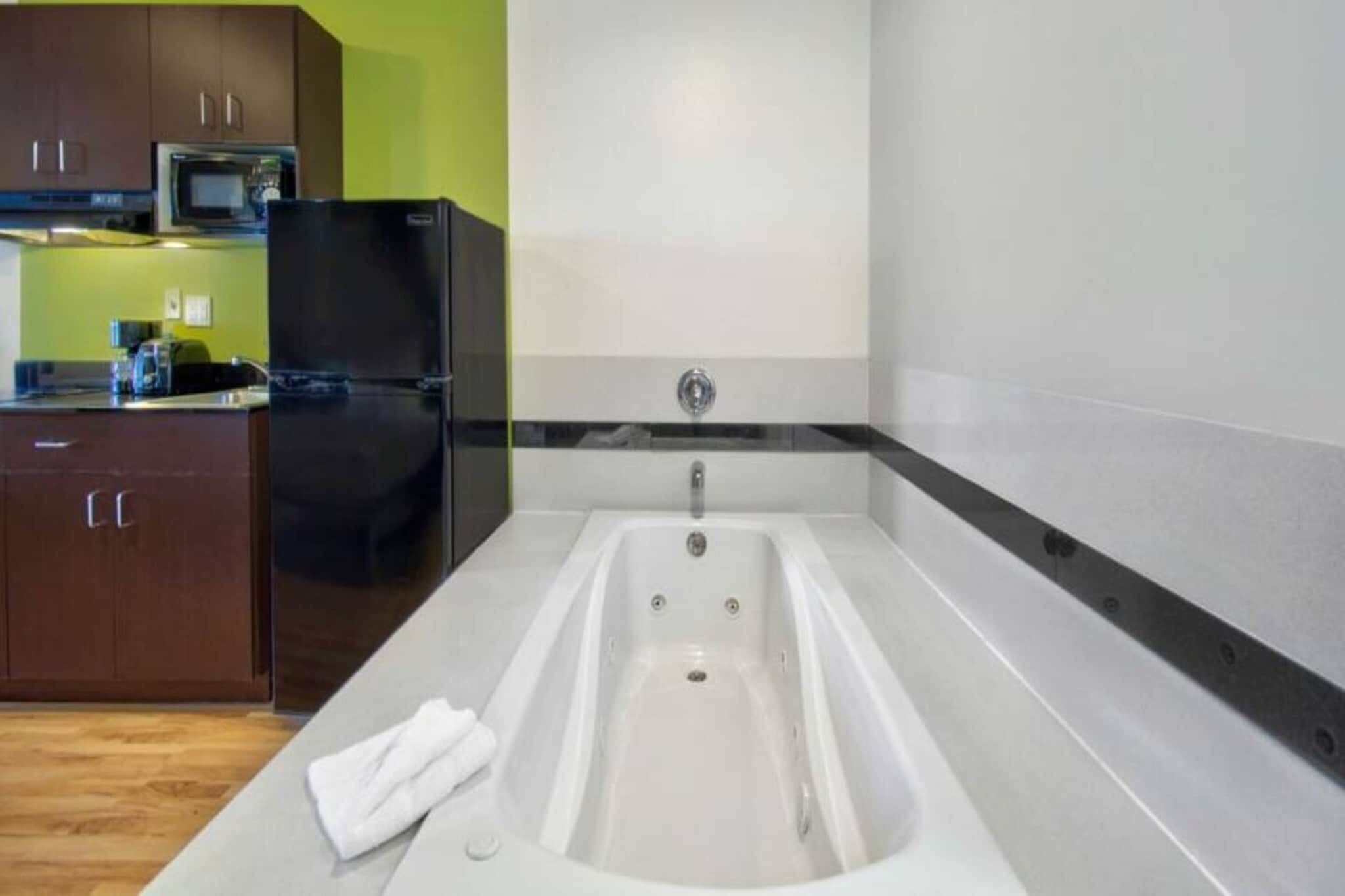 A modern kitchen with a built-in bathtub, a refrigerator, and a microwave.