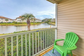A balcony with a green chair, a railing, and a view of a river with buildings in the background. - Walk to Ocean & Eats! Lake-View Myrtle Beach Haven (North Myrtle Beach)
