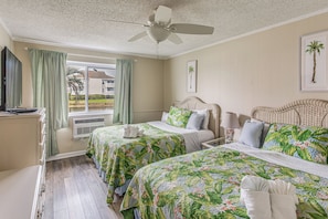 A hotel room with two beds, a ceiling fan, a window with curtains, and a view of the outside. - Walk to Ocean & Eats! Lake-View Myrtle Beach Haven (North Myrtle Beach)