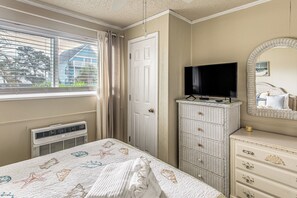 Ein Hotelzimmer mit Bett, Fernseher, Schminktisch und einem Fenster mit Vorhängen.