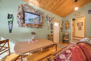 Ein rustikales Interieur mit einem Holztisch, Stühlen, einem Wand-Fernseher und verschiedenen Wanddekorationen, darunter ein Schädel und ein Schild.