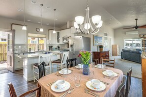 Una cocina moderna con una isla, comedor con una mesa lista para cuatro personas y una sala de estar con sofá.