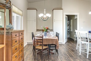 Comedor con una mesa dispuesta para cuatro personas, sillas, un aparador de madera y una lámpara colgante.