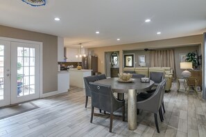 A modern kitchen with a dining area, featuring a central island, pendant lighting, and a view of the outdoors. - 3 Mi to Hobby Airport! Retreat w/ Poolside Oasis (Houston)