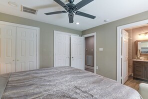 A bedroom with a bed, a ceiling fan, and a bathroom with a mirror and sink. - 3 Mi to Hobby Airport! Retreat w/ Poolside Oasis (Houston)
