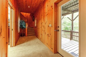 Corredor interno de madeira que dá para um deck com guarda-corpo.