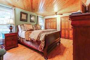 Ein Schlafzimmer mit Holzboden, einem Bett mit vielen Kissen, einem Nachttisch mit Lampe und einem Kleiderschrank.