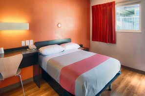 A hotel room with a bed, a bedside table with a phone, a chair, and a window with curtains. - 1 Full Bed | ADA/Tub (Mammoth Lakes)