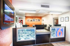 A reception desk with a digital screen displaying a scenic image, a sign with the number 6, and a framed picture of a forest. - 1 Full Bed | ADA/Tub (Mammoth Lakes)