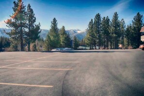 A parking lot with marked spaces, surrounded by trees and mountains in the background. - 1 Full Bed | ADA/Tub (Mammoth Lakes)