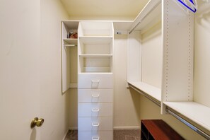 A walk-in closet with a built-in shelving unit, a wooden bench, and a door with a brass handle. - Work + Relax Poolside! Nurse-Ready Glendale Rental (Glendale)